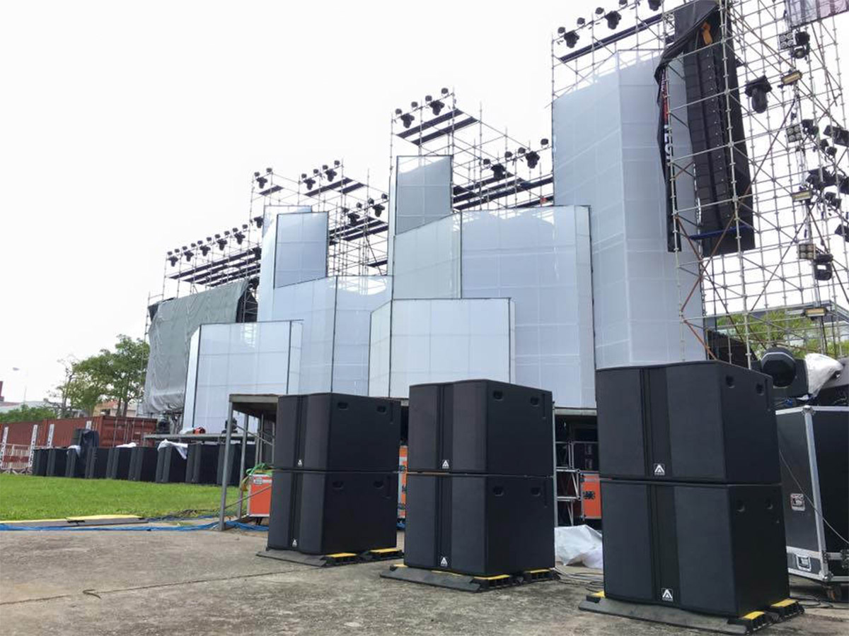 Amate subwoofer speakers stacked on the ground at a concert